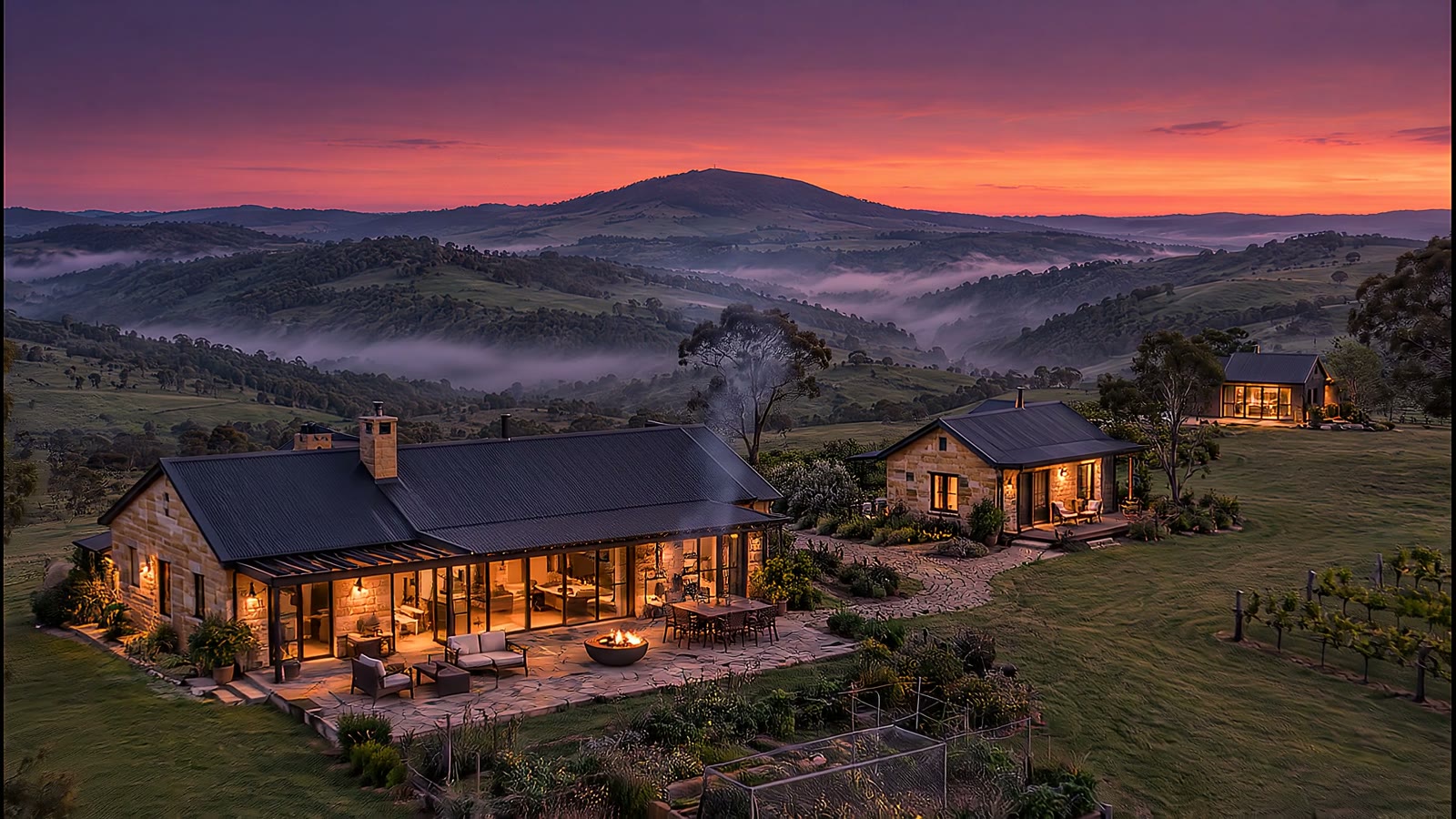 Dusk over an Adelaide Hills acreage with a sandstone home, a cottage and a barn studio, Mount Barker Summit behind